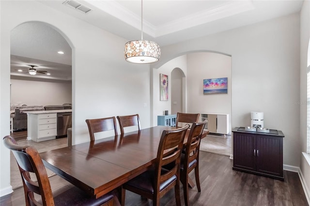 dining space featuring a raised ceiling, ceiling fan, crown molding, and dark hardwood / wood-style floors