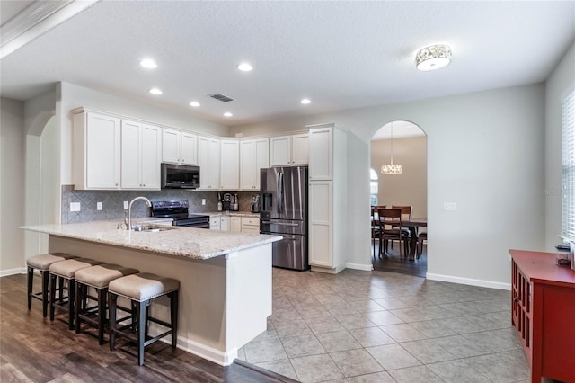 kitchen featuring sink, hanging light fixtures, stainless steel appliances, a breakfast bar area, and white cabinets