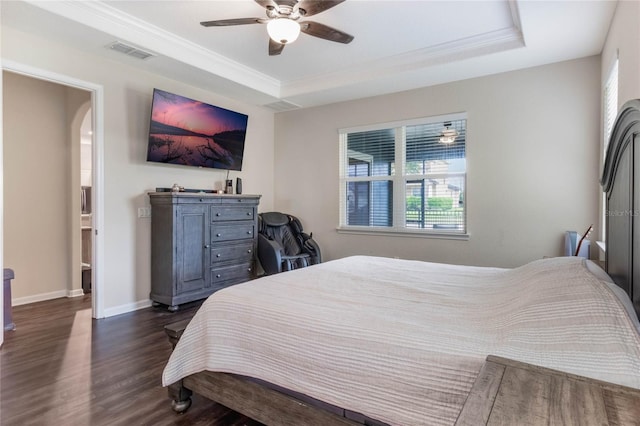 bedroom featuring dark hardwood / wood-style flooring, a tray ceiling, ceiling fan, and connected bathroom