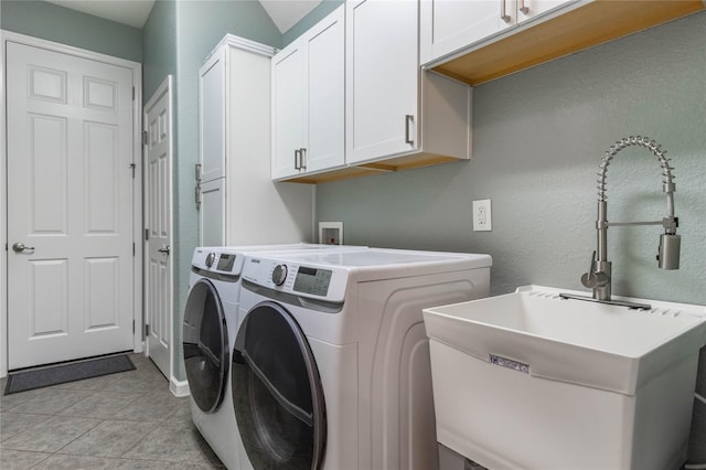 clothes washing area with light tile patterned flooring, cabinets, sink, and washing machine and dryer