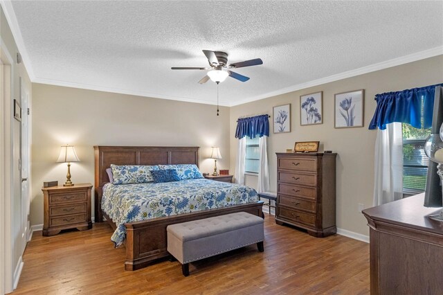 bedroom with ceiling fan, crown molding, multiple windows, and wood-type flooring