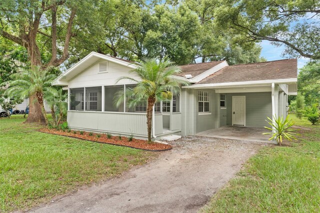 single story home with a carport, a sunroom, and a front yard