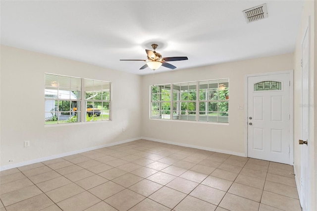 empty room featuring ceiling fan, light tile patterned floors, visible vents, and baseboards