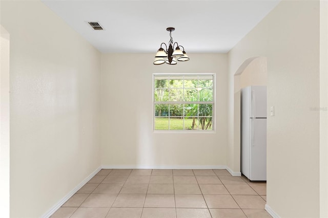 unfurnished dining area with arched walkways, light tile patterned floors, visible vents, an inviting chandelier, and baseboards