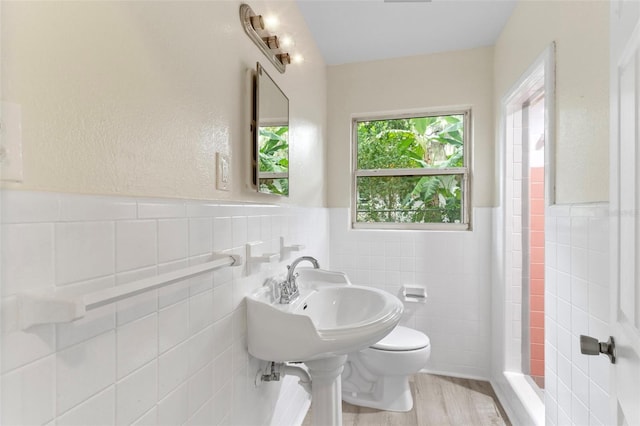 bathroom featuring toilet, a wainscoted wall, tile walls, and wood finished floors