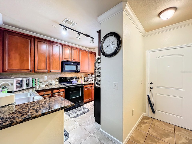 kitchen featuring light tile patterned flooring, dark stone countertops, ornamental molding, track lighting, and black appliances