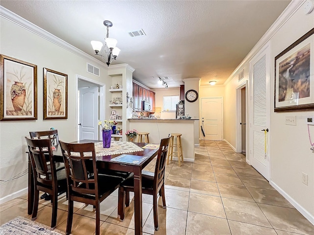 dining area with a textured ceiling, crown molding, a chandelier, and light tile patterned floors