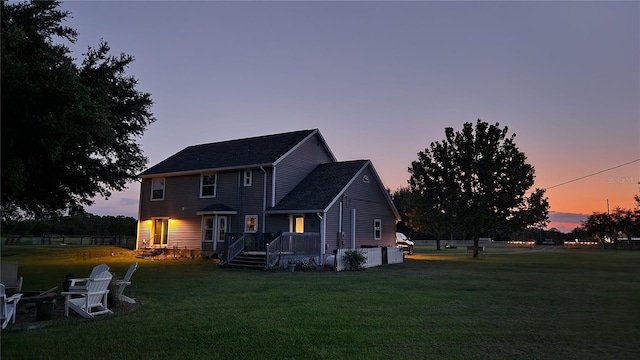 back house at dusk featuring a yard and a wooden deck