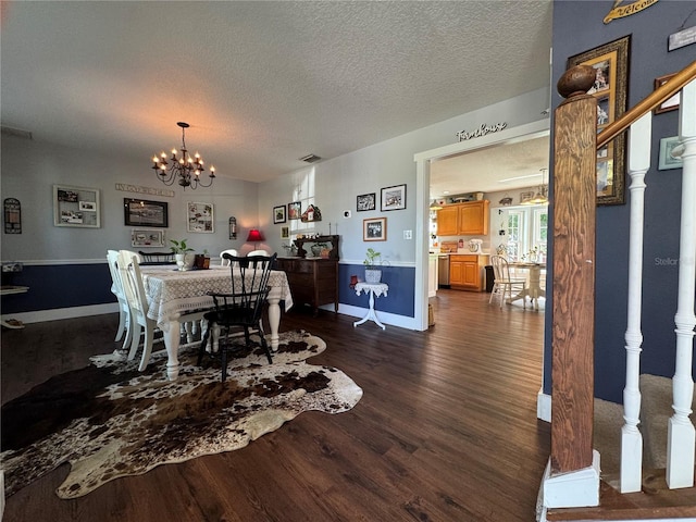 dining room with dark wood-type flooring, a textured ceiling, and a notable chandelier