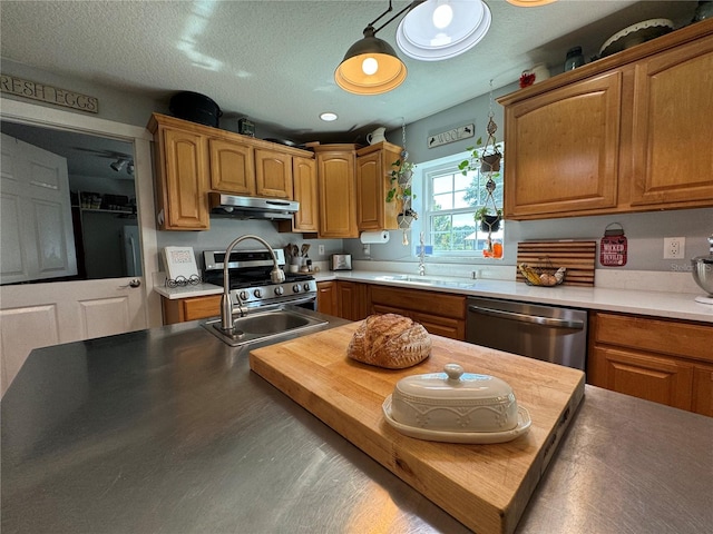 kitchen featuring pendant lighting, sink, stainless steel appliances, and a textured ceiling