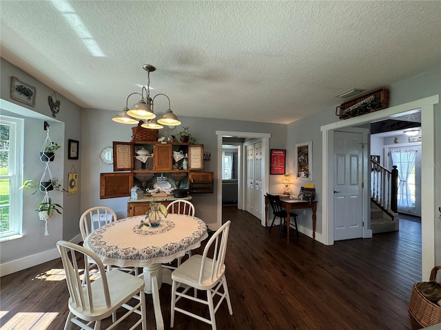 dining area with a textured ceiling, dark hardwood / wood-style floors, and a notable chandelier