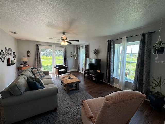 living room with dark hardwood / wood-style floors, a healthy amount of sunlight, a textured ceiling, and ceiling fan