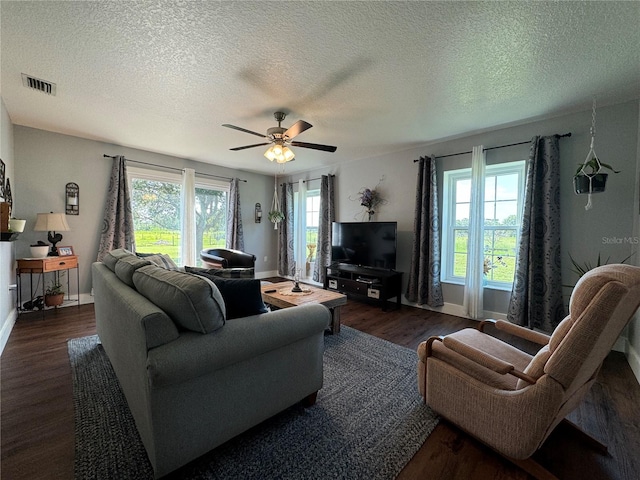 living room with ceiling fan, a healthy amount of sunlight, dark hardwood / wood-style flooring, and a textured ceiling