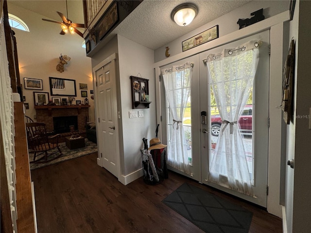 foyer entrance with ceiling fan, french doors, dark wood-type flooring, and a brick fireplace