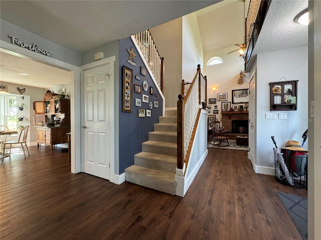 stairs featuring ceiling fan, a fireplace, wood-type flooring, and a textured ceiling