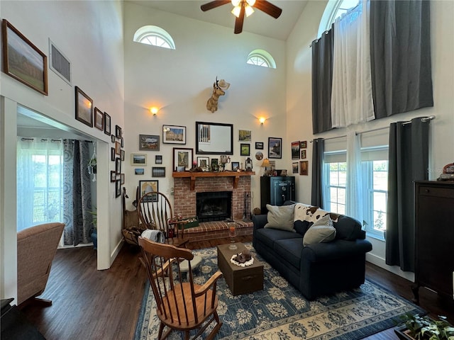 living room with ceiling fan, dark wood-type flooring, high vaulted ceiling, and a brick fireplace