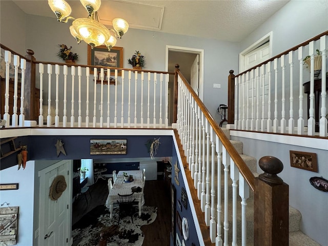 staircase with a notable chandelier and a textured ceiling