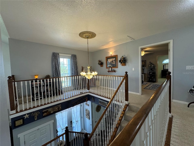 hall with carpet floors, a textured ceiling, and a chandelier