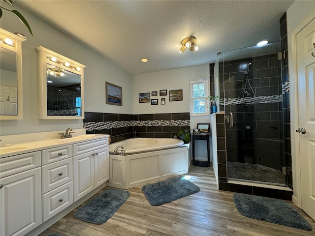 bathroom featuring a textured ceiling, shower with separate bathtub, vanity, tile walls, and hardwood / wood-style flooring