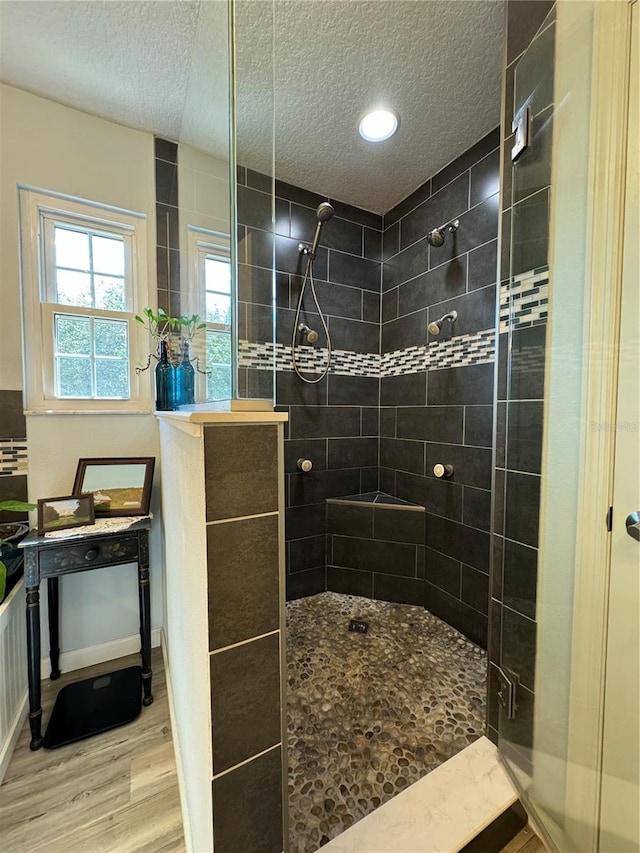 bathroom featuring hardwood / wood-style flooring, tiled shower, and a textured ceiling