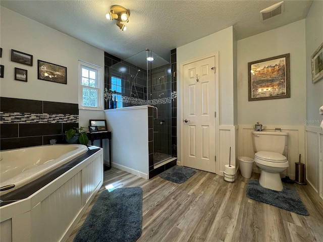 bathroom featuring a textured ceiling, hardwood / wood-style flooring, toilet, and a shower with shower door