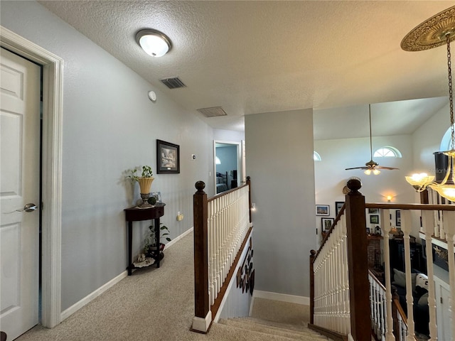 hallway with a textured ceiling and light colored carpet