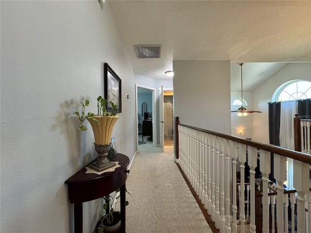 hallway featuring light carpet and a textured ceiling