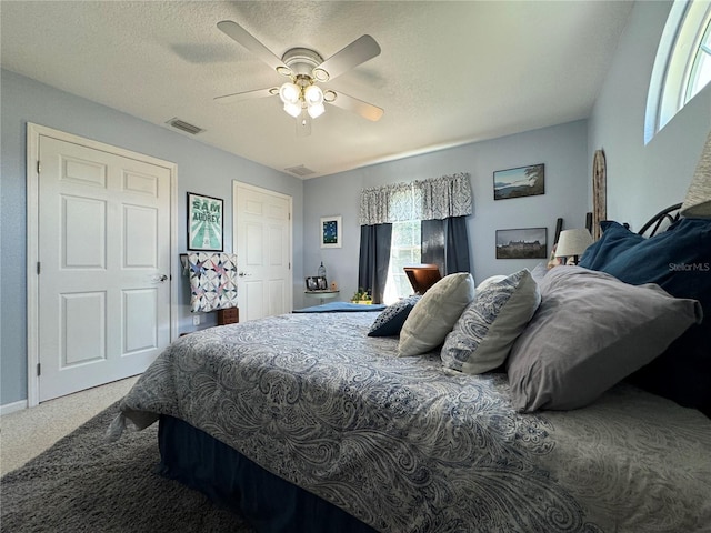 carpeted bedroom featuring ceiling fan and a textured ceiling