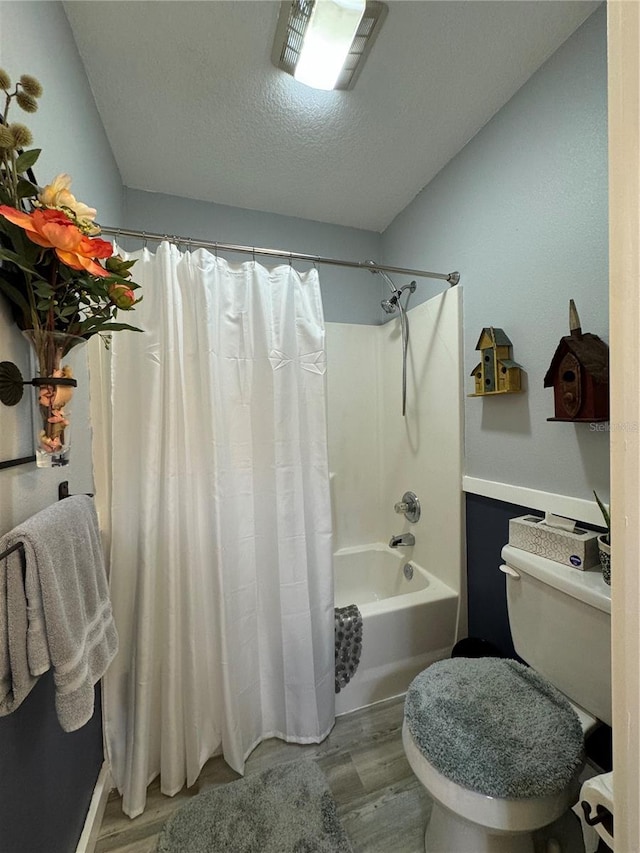 bathroom with a textured ceiling, toilet, shower / bath combo, and hardwood / wood-style flooring