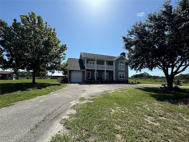 view of front of property featuring a front yard, a balcony, and a garage