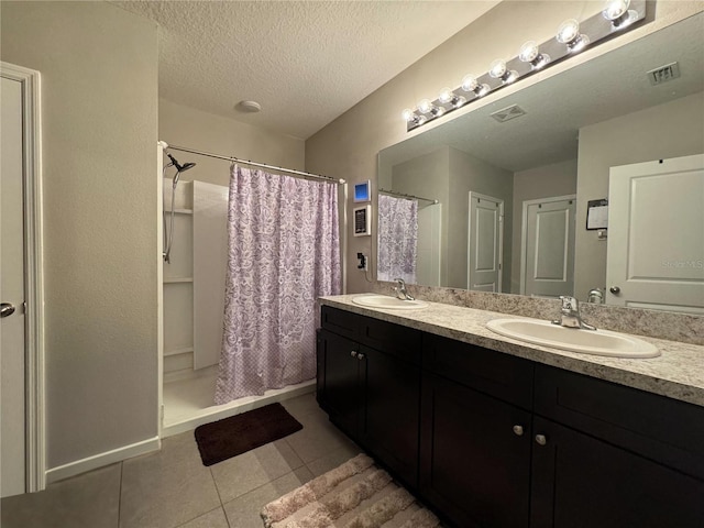 bathroom with tile patterned flooring, vanity, a shower with shower curtain, and a textured ceiling