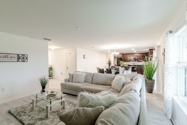 living room featuring an inviting chandelier and light hardwood / wood-style flooring