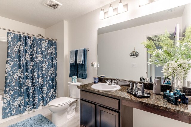 bathroom featuring tile patterned floors, a textured ceiling, vanity, toilet, and curtained shower