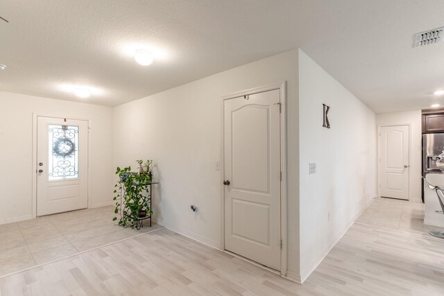 foyer entrance featuring a textured ceiling and light wood-type flooring