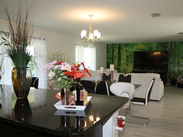 dining area with light hardwood / wood-style floors and an inviting chandelier