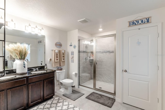 bathroom with tile patterned floors, vanity, a textured ceiling, toilet, and a shower with shower door