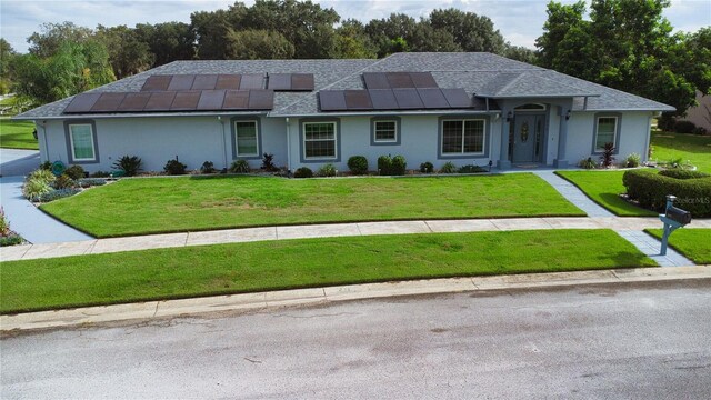 ranch-style house featuring a front lawn and solar panels