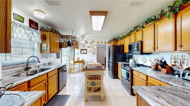 kitchen with light tile patterned flooring, sink, a kitchen island, ceiling fan, and stainless steel appliances