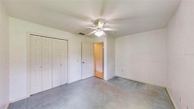 unfurnished bedroom with ceiling fan, carpet, and a closet