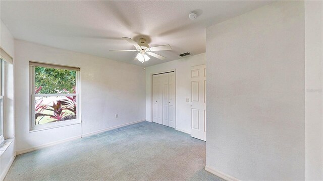 unfurnished bedroom featuring carpet flooring, ceiling fan, and a closet