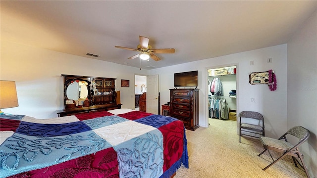 carpeted bedroom with ceiling fan, a closet, and a walk in closet