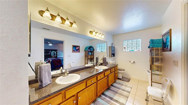 bathroom with ceiling fan, toilet, vanity, tile patterned floors, and a textured ceiling