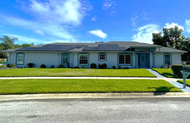 ranch-style house with solar panels and a front lawn