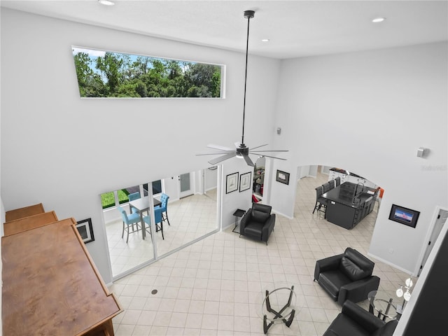 living room with ceiling fan and a high ceiling