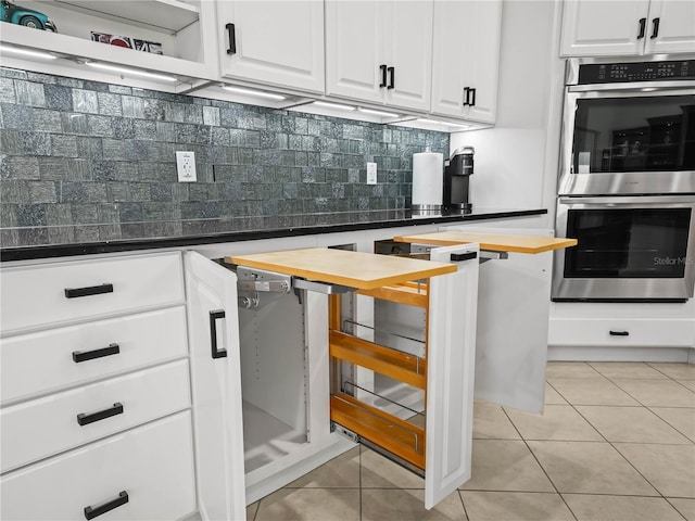 kitchen featuring light tile patterned floors, white cabinetry, butcher block countertops, double oven, and decorative backsplash