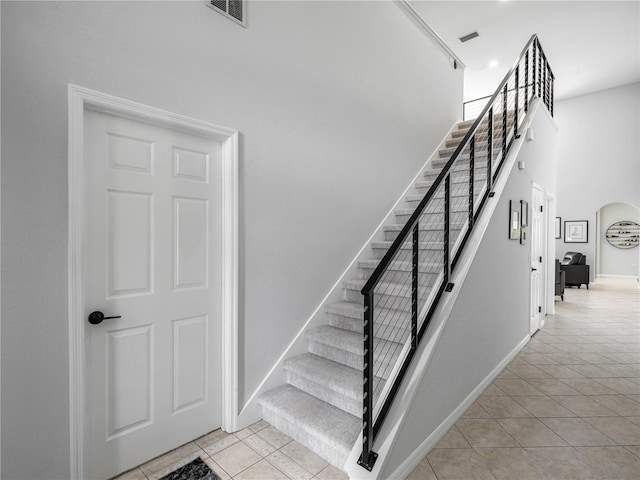 stairway with tile patterned flooring and a high ceiling