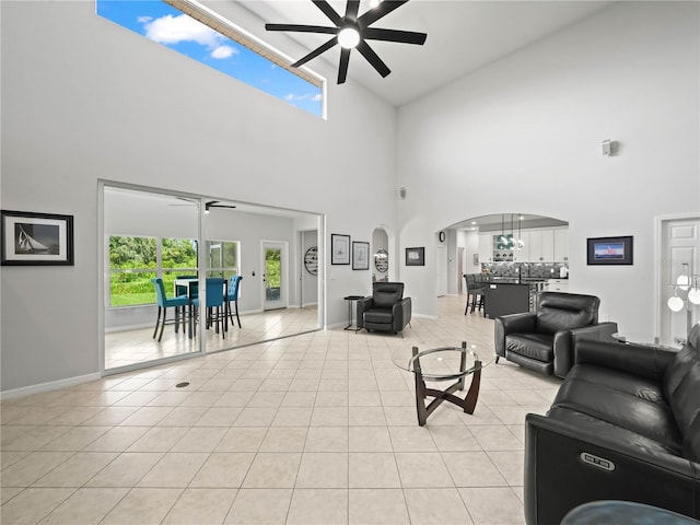 tiled living room with high vaulted ceiling, ceiling fan, and sink