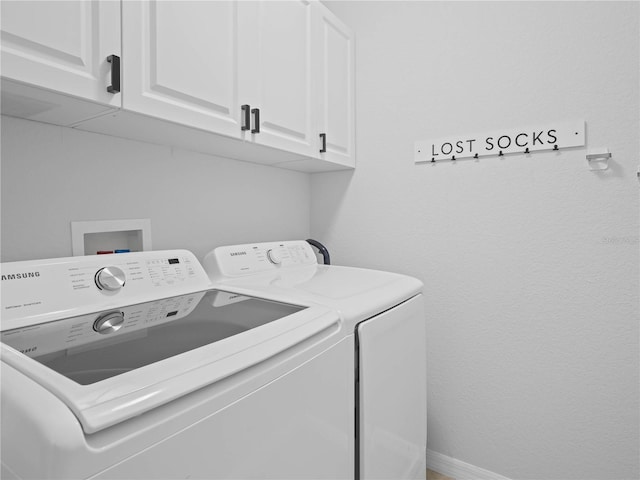 clothes washing area featuring cabinets and washer and clothes dryer