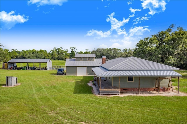 back of property featuring a chimney, metal roof, and a yard