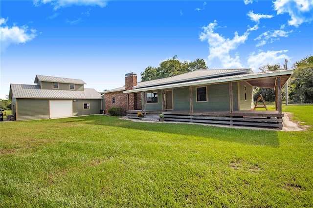 back of property with metal roof, a yard, a chimney, and covered porch